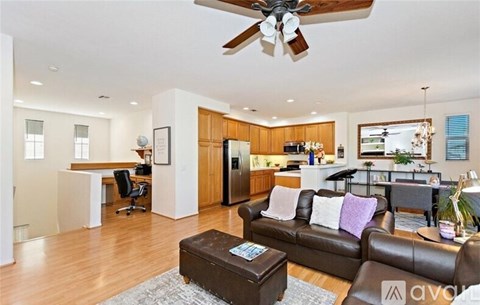 A living room with a brown couch and a ceiling fan.