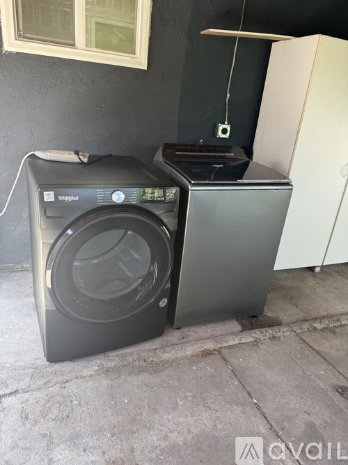 A front load washing machine is sitting outside a building.