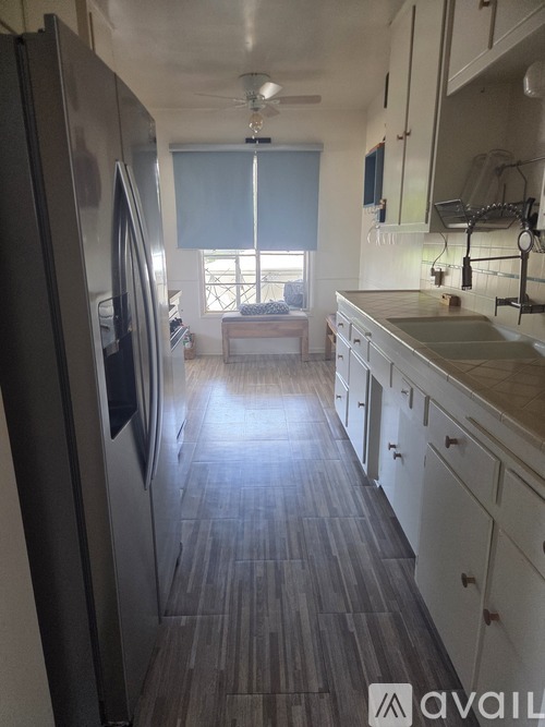 A kitchen with a refrigerator on the left and a counter on the right.