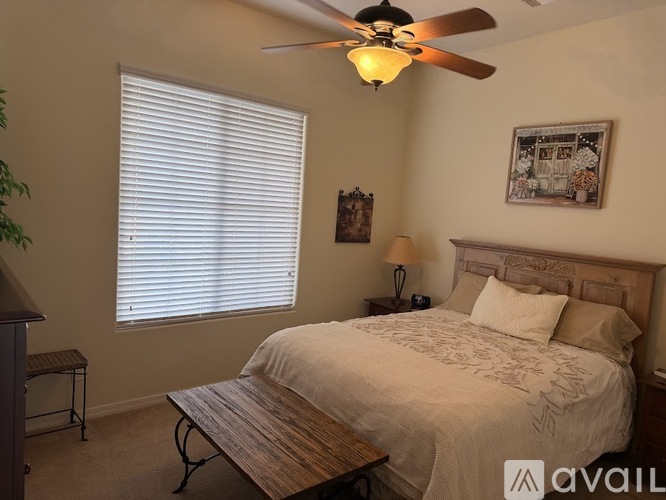 A bedroom with a bed, a table, and a ceiling fan.