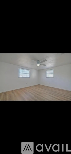 A room with a ceiling fan and two windows.