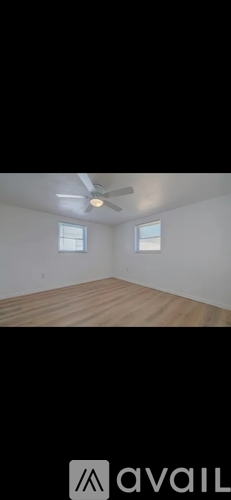 A room with a ceiling fan and two windows.