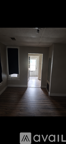 A room with wooden floors and a door leading to another room.