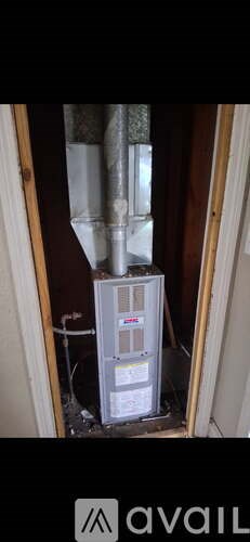 A white heating unit is installed in a narrow space between two walls.