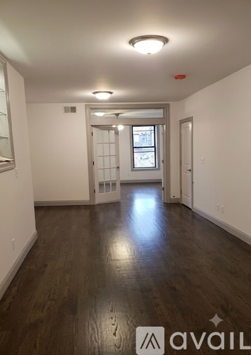 A room with wooden floors and a window with blinds.