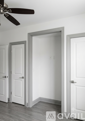 A room with a ceiling fan and three doors.