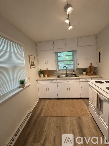 A kitchen with white cabinets and a wooden floor.