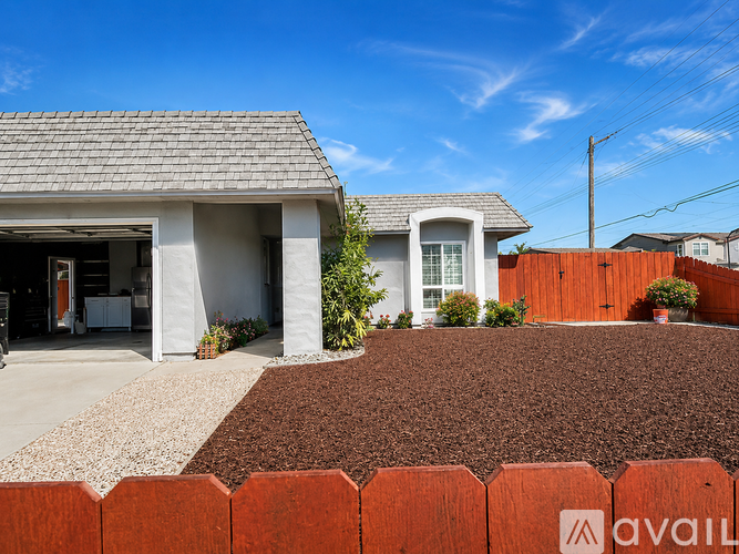 A house with a brown fence and a gravel driveway.