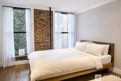 A bedroom with a large bed and a brick wall.