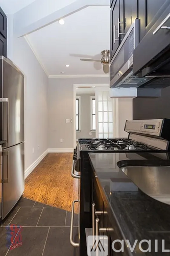 A modern kitchen with stainless steel appliances and wooden flooring.