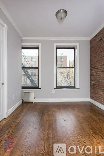 A room with wooden floors and two windows.