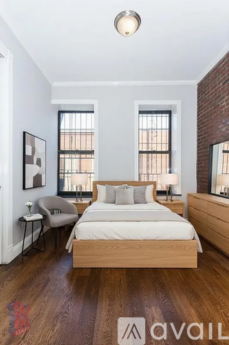 A bedroom with a large bed, a chair, and a painting on the wall.