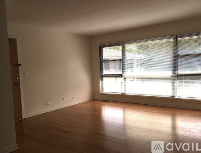 A room with wooden floors and a window with blinds.