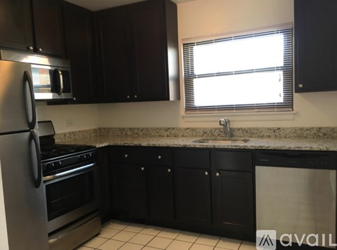 A kitchen with black cabinets and a stainless steel refrigerator.