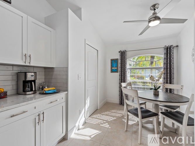 A kitchen with white cabinets and a black coffee maker.