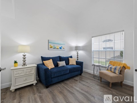 A living room with a blue couch, a white dresser, and a painting on the wall.
