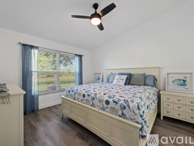 A bedroom with a bed, dresser, and ceiling fan.