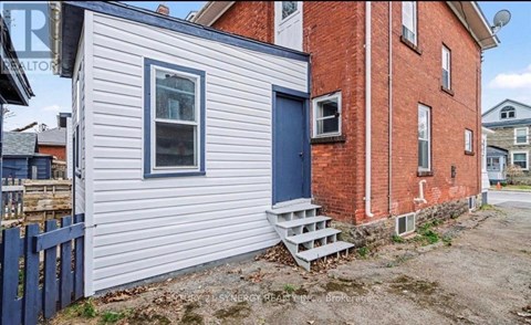 A small house with a blue door and a red brick building behind it.