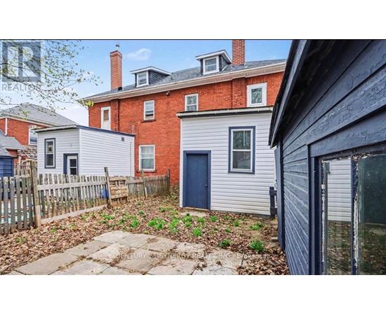 A red brick house with a blue door and a grey house with a blue door in front of it.
