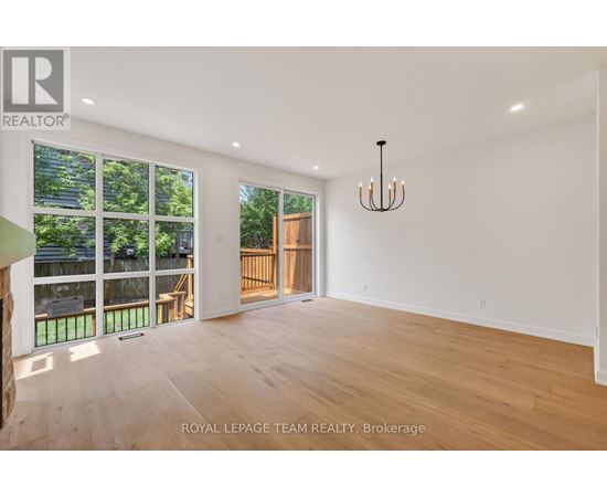 A spacious room with wooden floors and a chandelier.