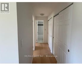 A hallway with white walls and wooden floors leading to a door.