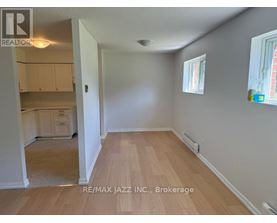 A room with wooden flooring and white walls, with a window on the right side.