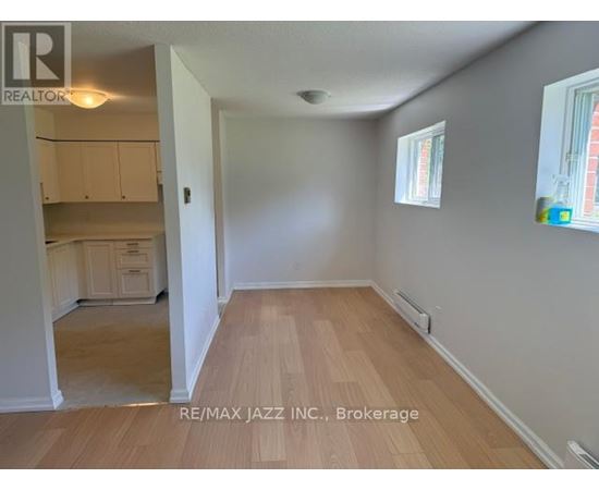 A room with wooden flooring and white walls, with a window on the right side.
