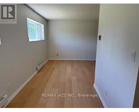 A room with wooden flooring and a window on the left wall.
