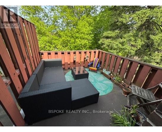 A wooden deck with a hot tub and a black sofa.