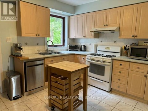 A kitchen with wooden cabinets and a white stove top oven.