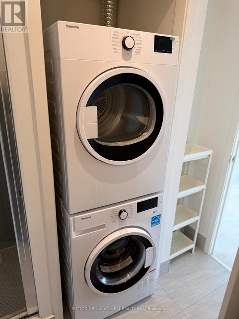 A white front loading washing machine with a black door is in a room.