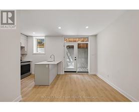 A white room with a kitchen island and a door leading to a balcony.