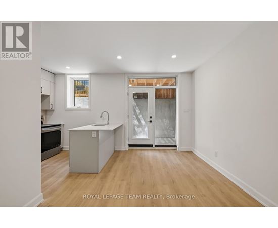 A white room with a kitchen island and a door leading to a balcony.
