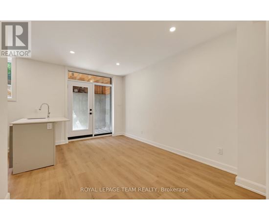 A spacious room with wooden flooring and a white wall.