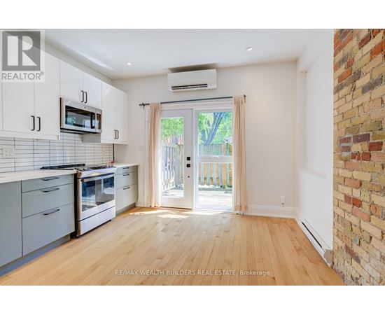 A kitchen with white cabinets and a brick wall.