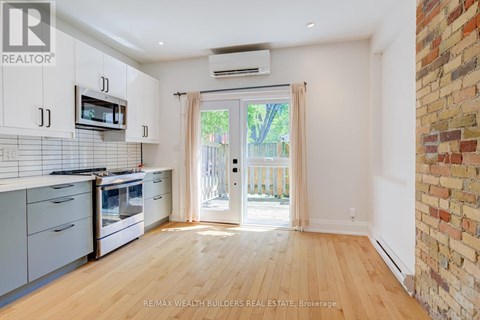 A kitchen with white cabinets and a brick wall.