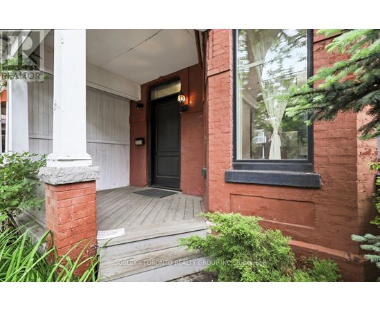 A red brick house with a black door and a small porch.