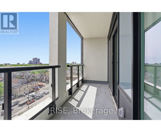 A balcony with a view of a parking lot and buildings.