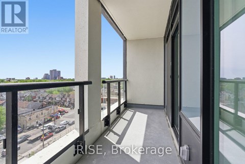 A balcony with a view of a parking lot and buildings.