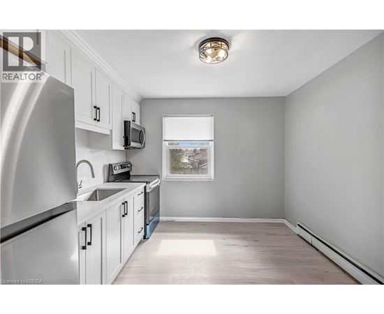 A kitchen with white cabinets and a stainless steel refrigerator.