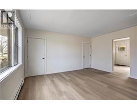 A room with wooden floors and white walls, with a window on the left side.
