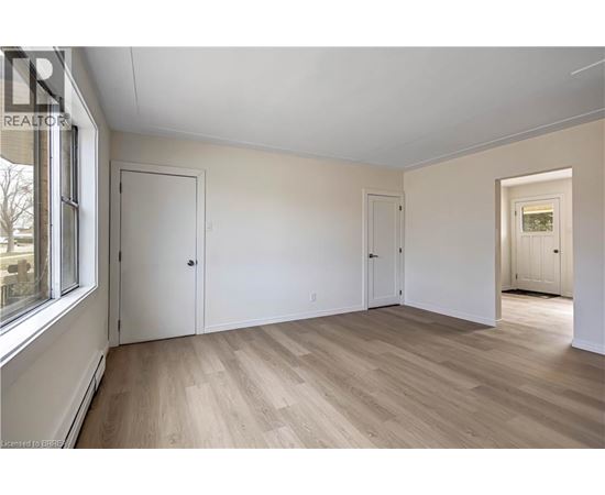 A room with wooden floors and white walls, with a window on the left side.
