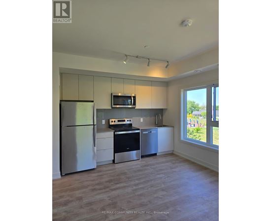 A kitchen with a refrigerator, microwave, oven, and cabinets.