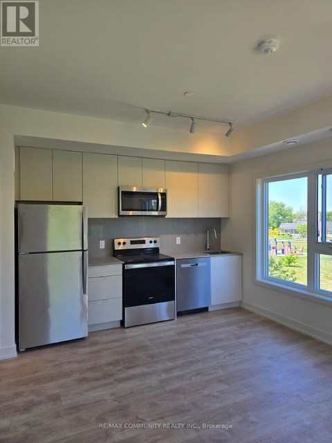 A kitchen with a refrigerator, microwave, oven, and cabinets.