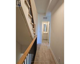 A hallway with a staircase on the left and a doorway leading to another room on the right.