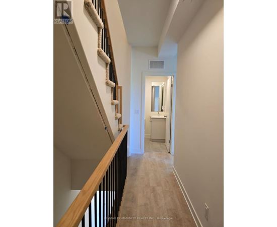A hallway with a staircase on the left and a doorway leading to another room on the right.