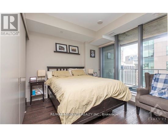 A bedroom with a bed, chair, and window.
