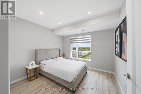 A bedroom with a large bed and a nightstand with a lamp.