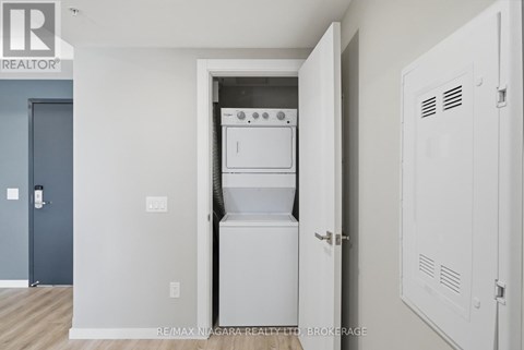 A white kitchen appliance is in a white cabinet in a white room.