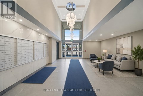 A spacious lobby with a blue carpet and a glass ceiling light fixture.